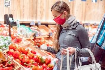 A woman wearing a face covering shops for groceries. File photo courtesy of © Can Stock Photo / Kzenon