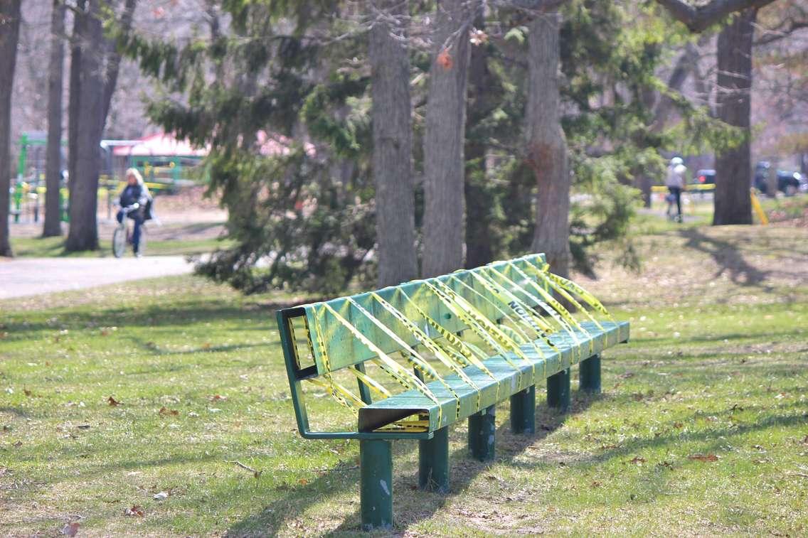 Cyclists ride by a caution-taped bench at Sarnia's Canatara Park (BlackburnNews.com photo by Dave Dentinger)