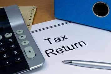 Tax return papers lying next to folder and calculator. © Can Stock Photo / gcpics