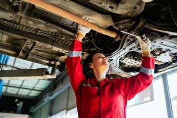 A woman working on a vehicle (Photo by: iStock / Getty Images Plus/ 	Artit_Wongpradu)