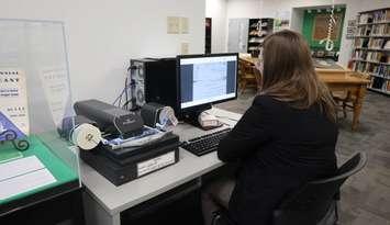 A visitor browses a Moore Township Paper on microfilm. (Photo by: County of Lambton)