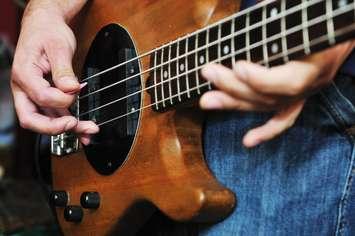 A bass player strumming his instrument. © Can Stock Photo / dotshock