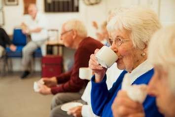 A woman enjoys a coffee with friends. 	DGLimages / iStock / via Getty Images Plus 