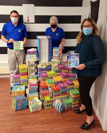 A mountain of books pictured with Rotary president, Mike Elliot, and Johnna Johansen
(back left) (Photo courtesy of Literacy Lambton)