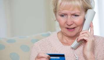 Senior woman giving credit card details on the phone. © Can Stock Photo / daisydaisy