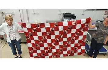 Staff at Great Pretenders, also known as Creative Education of Canada, show off a quilt made for local shelters. June 15, 2022 Image courtesy of Julie Donald.