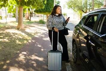 A woman waiting for a rideshare service car. Antonio_Diaz via Getty Images Plus.