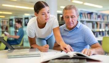 Young woman explaining information to a mature man in the library. Photo by JackF / iStock / Getty Images Plus via Getty Images.