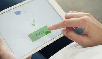 A woman taps the vote button on a digital tablet. Photo by Anton_Sokolov / iStock / Getty Images Plus via Getty Images