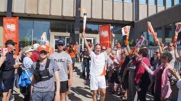Wes Harding holds the first torch high at Sarnia Pan Am Games celebration outside City Hall June 16, 2015 (BlackburnNews.com Photo by Briana Carnegie)