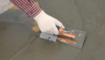 Construction worker with trowel spreading wet concrete. (© Can Stock Photo / Stockphoto)