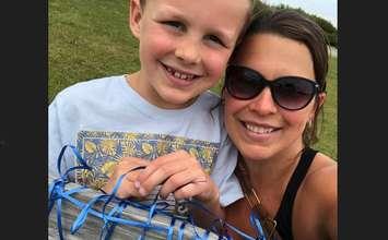 Jodi McCormick and her son Jimmy tie a blue ribbon on a memorial bench for Noelle Paquette while participating in Count Your K's In May. Submitted photo.