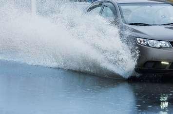A car driving on a flooded road. © Can Stock Photo / dbrus