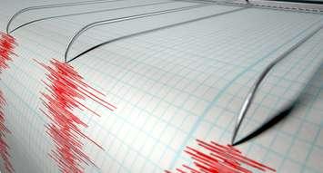 A closeup of a seismograph machine needle drawing a red line on graph paper depicting seismic and eartquake activity on an isolated white background. © Can Stock Photo / albund