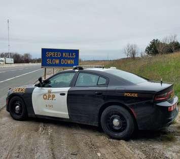 OPP cruiser next to a "Speed Kills - Slow Down" sign on the highway. (Photo by OPP West Region)