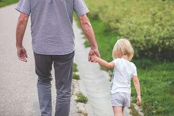 A young girl holding hands with a man. (Photo from Pxfuel)
