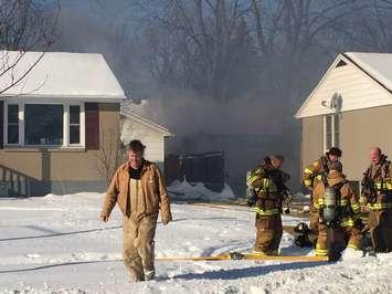 Homeowner Chris Biggs walks away from the scene as crews work to extinguish a fire that fully engulfed his garage on Minto St. January 9, 2018 (Photo by Melanie Irwin)
