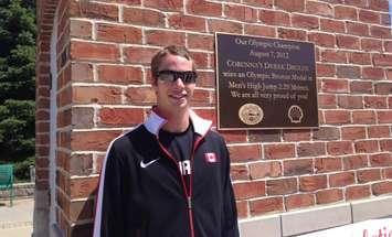 Derek Drouin poses beside a plaque erected in his honour in Corunna recognizing his bronze medal win in 2012 (BlackburnNews.com file photo)