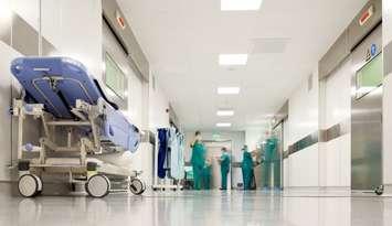 Blurred figures of people with medical uniforms in hospital corridor. © Can Stock Photo / VILevi