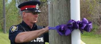 Sarnia Police Constable Chris Moxley places a purple ribbon at Indian Rd. and Exmouth St. May 17, 2016 (BlackburnNews.com Photo by Briana Carnegie)