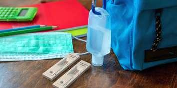 School coronavirus protection concept. rapid test, hand sanitizer and student backpack on wooden desk. © Can Stock Photo / rawf8