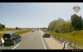 A dark sedan seen driving on the shoulder of HWY 401 in Elgin County. Photo captured via footage supplied by OPP.