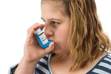 A girl using her asthma inhaler. File photo courtesy of © Can Stock Photo / dragon_fang.