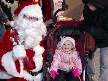 A little girl with Santa Claus at the Corunna Santa Claus Parade. (Photo by the Optimist Club of Moore)